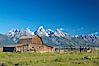 An old barn at Mormon Row is lit by the morning sun with the Teton Range rising in the distance. Mormon Row, Grand Teton National Park, Wyoming, USA. Image #12998