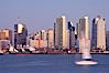 San Diego city skyline at dusk, viewed from Harbor Island, a sailboat cruises by in the foreground, the Star of India at left. San Diego, California, USA. Image #14526