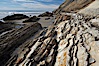 Shale is a fine-grained detrital sedimentary rock formed by the compaction of clay, silt, or mud.  Shale is formed when mud is pressed into rock over millions of years and often breaks into big flat pieces. Here layers of shale emerge from the sand and cliffs at Gaviota State Beach north of Santa Barbara. Gaviota State Beach, Santa Barbara, California, USA. Image #14898