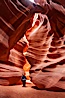 A hiker admiring the striated walls and dramatic light within Antelope Canyon, a deep narrow slot canyon formed by water and wind erosion. Navajo Tribal Lands, Page, Arizona, USA. Image #17996