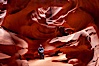 A hiker admiring the striated walls and dramatic light within Antelope Canyon, a deep narrow slot canyon formed by water and wind erosion. Navajo Tribal Lands, Page, Arizona, USA. Image #18009