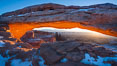 Mesa Arch spans 90 feet and stands at the edge of a mesa precipice thousands of feet above the Colorado River gorge. For a few moments at sunrise the underside of the arch glows dramatically red and orange. Island in the Sky, Canyonlands National Park, Utah, USA. Image #18040