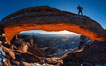 Mesa Arch, Utah.  An hiker watches the dawning sun from atop Mesa Arch. Island in the Sky, Canyonlands National Park, USA