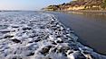 Ocean water washes over a flat sand beach, sandstone bluffs rise in the background, sunset. Carlsbad, California, USA. Image #19806