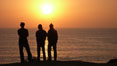 Surf check.  Three guys check the surf from atop a bluff overlooking the waves at the end of the day, at sunset, north of South Carlsbad State Beach. California, USA. Image #19808