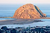Morro Rock lit at sunrise, rises above Morro Bay which is still in early morning shadow. Morro Bay, California, USA. Image #22219