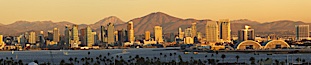 San Diego city skyline, showing the buildings of downtown San Diego rising above San Diego Harbor, viewed from Point Loma at sunset, with mountains of the Cleveland National Forest rising in the distance.  A panoramic photograph, composite of six separate images. San Diego, California, USA. Image #22252