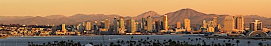 San Diego city skyline, showing the buildings of downtown San Diego rising above San Diego Harbor, viewed from Point Loma at sunset, with mountains of the Cleveland National Forest rising in the distance. A panoramic photograph, composite of seven separate images. San Diego, California, USA. Image #22257