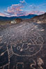 Sky Rock petroglyphs near Bishop, California, sunrise light just touching clouds and the Sierra Nevada. Hidden atop an enormous boulder in the Volcanic Tablelands lies Sky Rock, a set of petroglyphs that face the sky.  These superb examples of native American petroglyph artwork are thought to be Paiute in origin, but little is known about them. USA. Image #26979