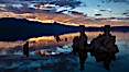 Tufa towers rise from Mono Lake, with the Eastern Sierra visible in the distance. Tufa towers are formed when underwater springs rich in calcium mix with lakewater rich in carbonates, forming calcium carbonate (limestone) structures below the surface of the lake. The towers were eventually revealed when the water level in the lake was lowered starting in 1941. Mono Lake, California, USA. Image #26983