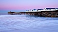 The Crystal Pier and Pacific Ocean at sunrise, dawn, waves blur as they crash upon the sand.  Crystal Pier, 872 feet long and built in 1925, extends out into the Pacific Ocean from the town of Pacific Beach. Pacific Beach, California, USA. Image #27243