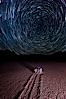 Racetrack sailing stone and star trails.  A sliding rock of the Racetrack Playa. The sliding rocks, or sailing stones, move across the mud flats of the Racetrack Playa, leaving trails behind in the mud. The explanation for their movement is not known with certainty, but many believe wind pushes the rocks over wet and perhaps icy mud in winter. Racetrack Playa, Death Valley National Park, California, USA. Image #27671