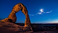 Delicate Arch and the Moon at Sunset.  The moon and clouds, with stars showing faintly in the sky, as sunset fades into night. Arches National Park, Utah, USA. Image #27859