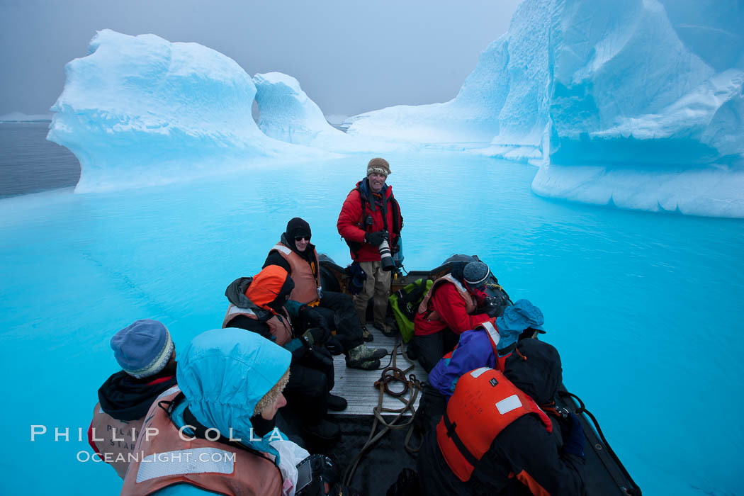 Visitors enjoy an inflatable ride through the strange environs of a bizarrely-shaped iceberg, on a cloudy day. Brown Bluff, Antarctic Peninsula, Antarctica, natural history stock photograph, photo id 24995