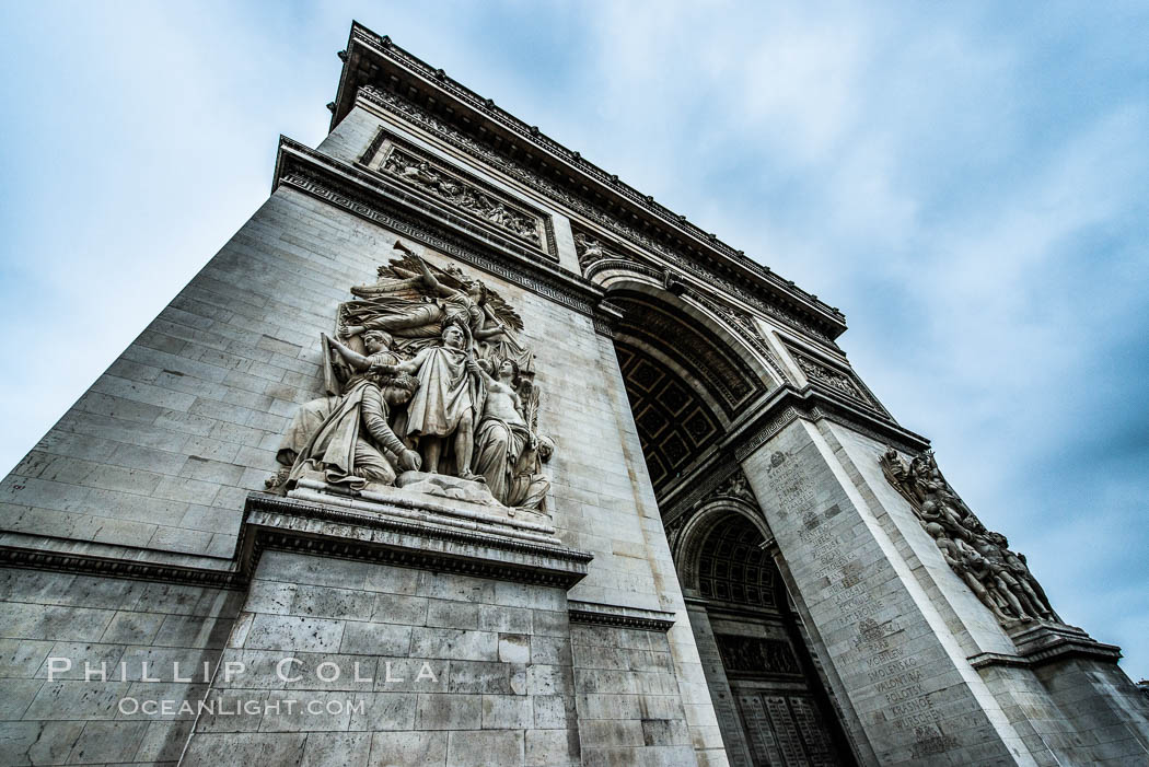 Arc de Triomphe. The Arc de Triomphe (Arc de Triomphe de l'Etoile) is one of the most famous monuments in Paris. It stands in the centre of the Place Charles de Gaulle (originally named Place de l'Etoile), at the western end of the Champs-Elysees. The Arc de Triomphe (in English: "Triumphal Arch") honors those who fought and died for France in the French Revolutionary and the Napoleonic Wars, with the names of all French victories and generals inscribed on its inner and outer surfaces. Beneath its vault lies the Tomb of the Unknown Soldier from World War I. The monument was designed by Jean Chalgrin in 1806, and its iconographic program pitted heroically nude French youths against bearded Germanic warriors in chain mail. It set the tone for public monuments, with triumphant patriotic messages. The monument stands 50 metres (164 ft) in height, 45 m (148 ft) wide and 22 m (72 ft) deep