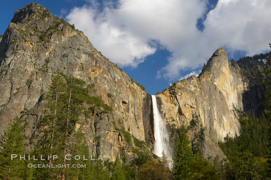 Bridalveil Falls at sunset, with clouds and blue sky in the background. Bridalveil Falls in Yosemite drops 620 feet (188 m) from a hanging valley to the floor of Yosemite Valley, Yosemite National Park, California