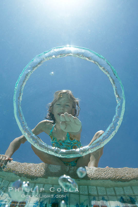 A bubble ring. A young girl reaches out to touch a bubble ring as it ascends through the water toward her