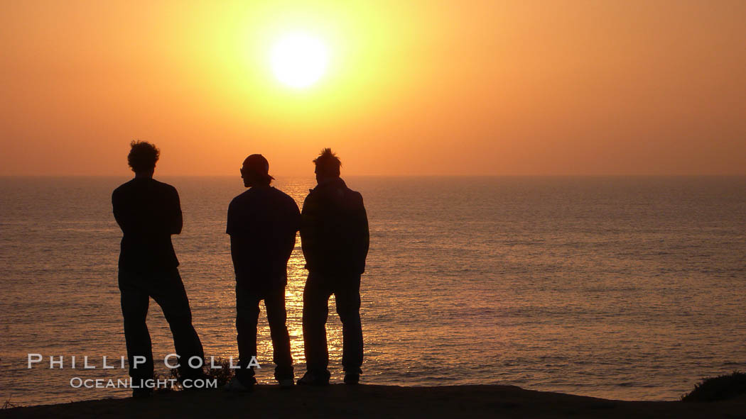 Surf check.  Three guys check the surf from atop a bluff overlooking the waves at the end of the day, at sunset, north of South Carlsbad State Beach