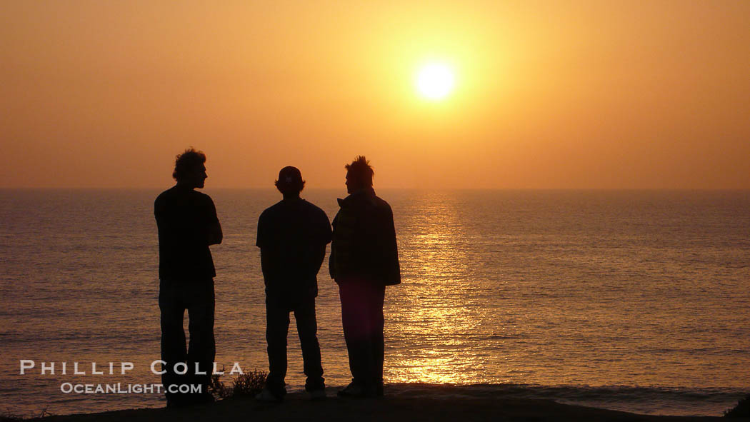 Surf check.  Three guys check the surf from atop a bluff overlooking the waves at the end of the day, at sunset, north of South Carlsbad State Beach., natural history stock photograph, photo id 19821