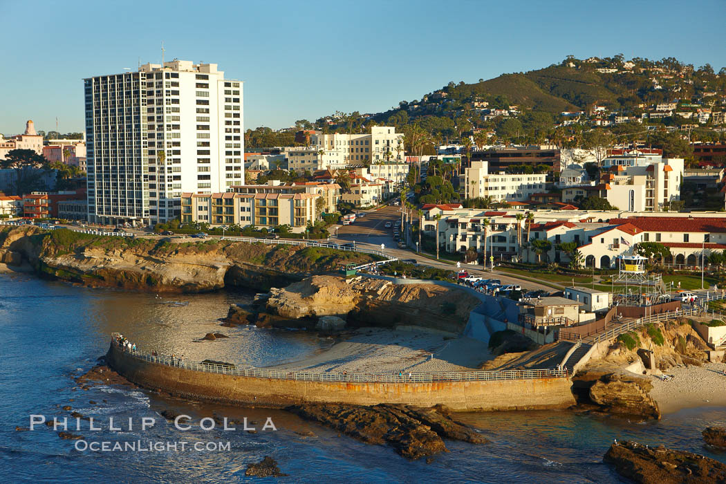 The Children's Pool in La Jolla, also known as Casa Cove, is a small pocket cove protected by a curving seawall, with the rocky coastline and cottages and homes of La Jolla seen behind it