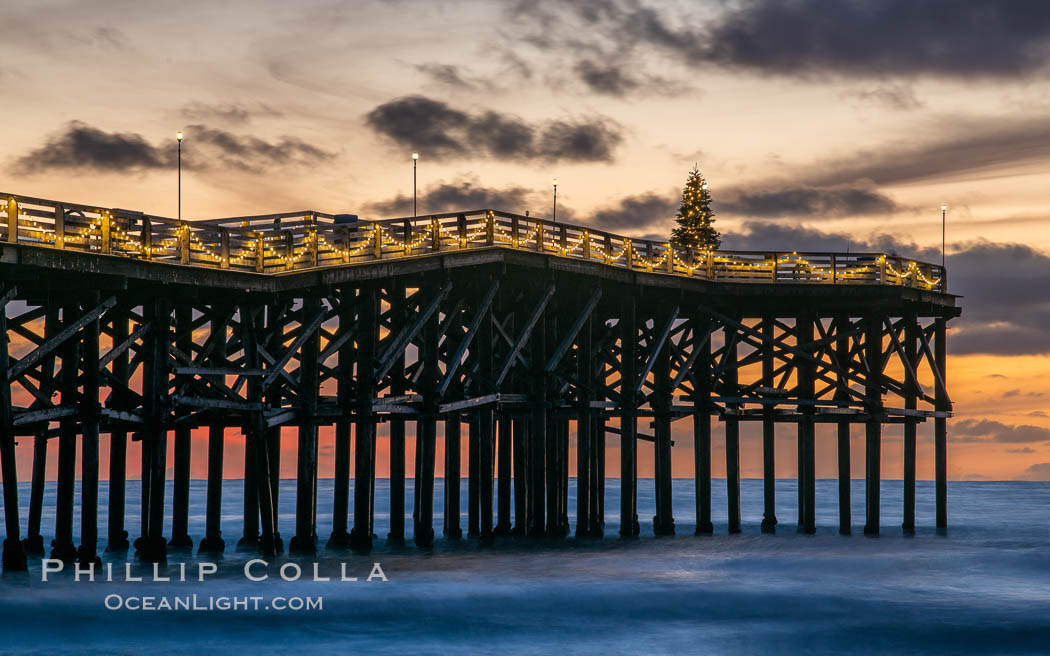 The Crystal Pier, Holiday Lights and Pacific Ocean at sunset, waves blur as they crash upon the sand. Crystal Pier, 872 feet long and built in 1925, extends out into the Pacific Ocean from the town of Pacific Beach., natural history stock photograph, photo id 37560