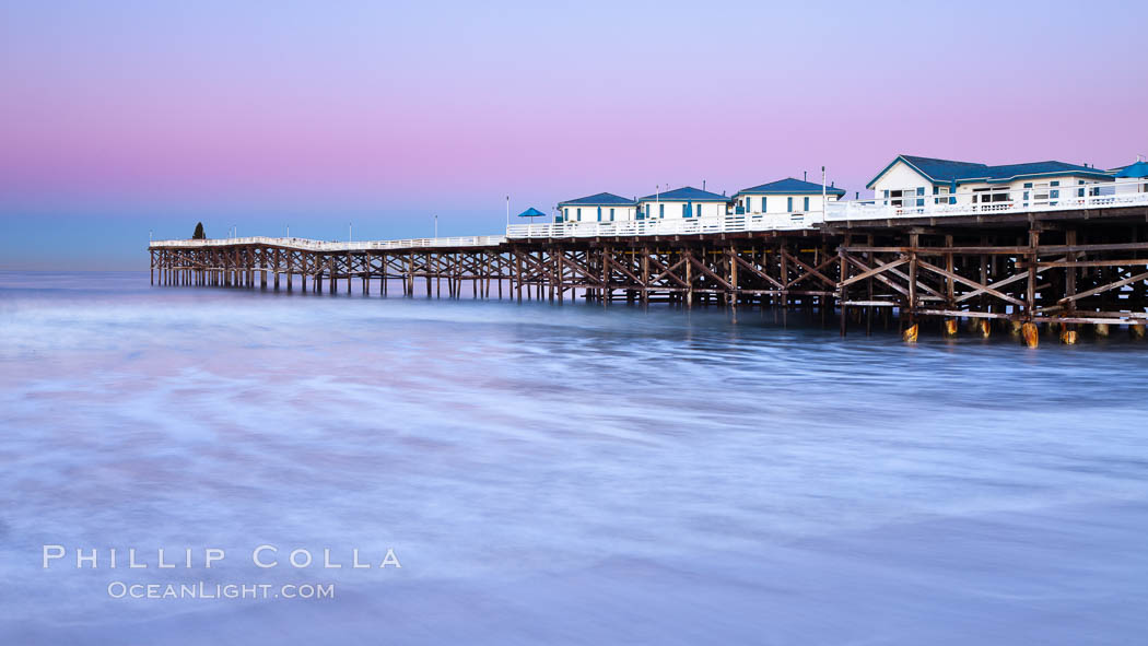 The Crystal Pier and Pacific Ocean at sunrise, dawn, waves blur as they crash upon the sand.  Crystal Pier, 872 feet long and built in 1925, extends out into the Pacific Ocean from the town of Pacific Beach