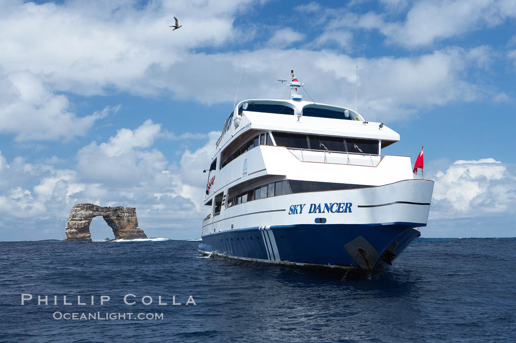 Sky Dancer, a liveaboard dive tour boat, at anchor near Darwin Island with Darwins Arch in the background. Galapagos Islands, Ecuador, natural history stock photograph, photo id 16691