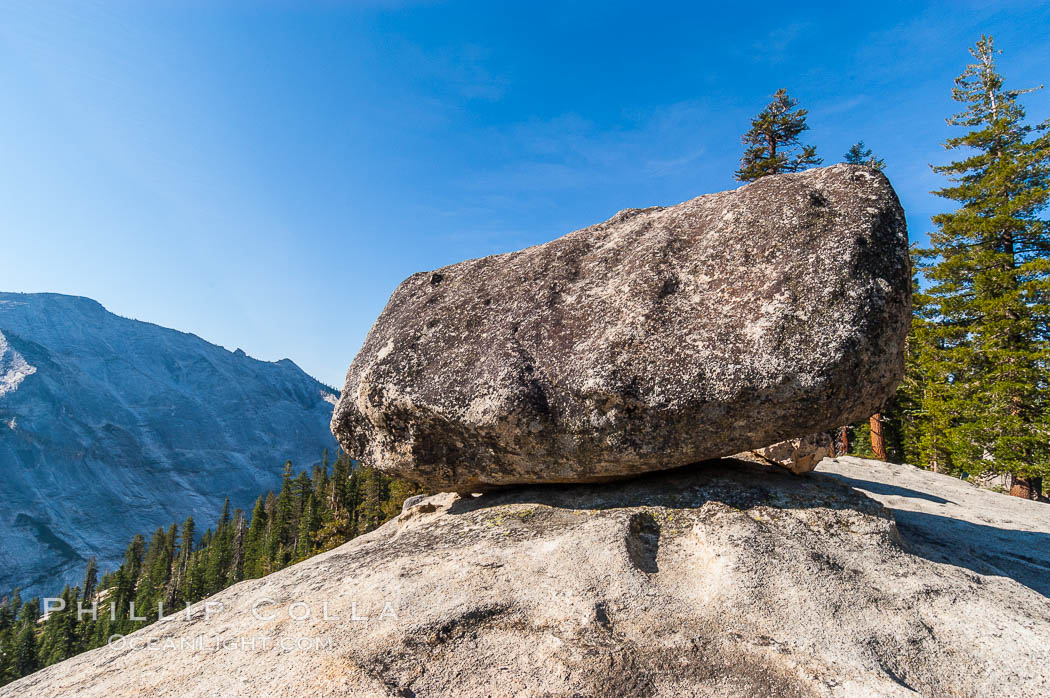 A glacial erratic hangs precariously at the precipice to Tenaya Canyon, with Clouds Rest in the background. Erratics are huge boulders left behind by the passing of glaciers which carved the granite surroundings into their present-day form, Yosemite National Park, California