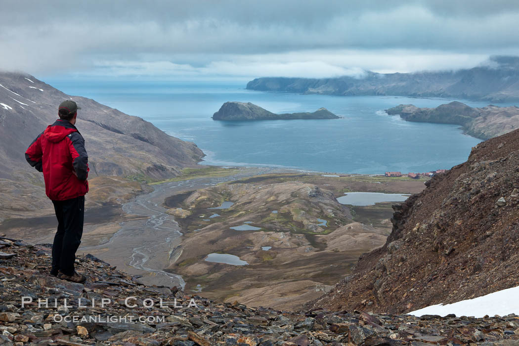 Hiker looks down on Stromness Harbour from the pass high above