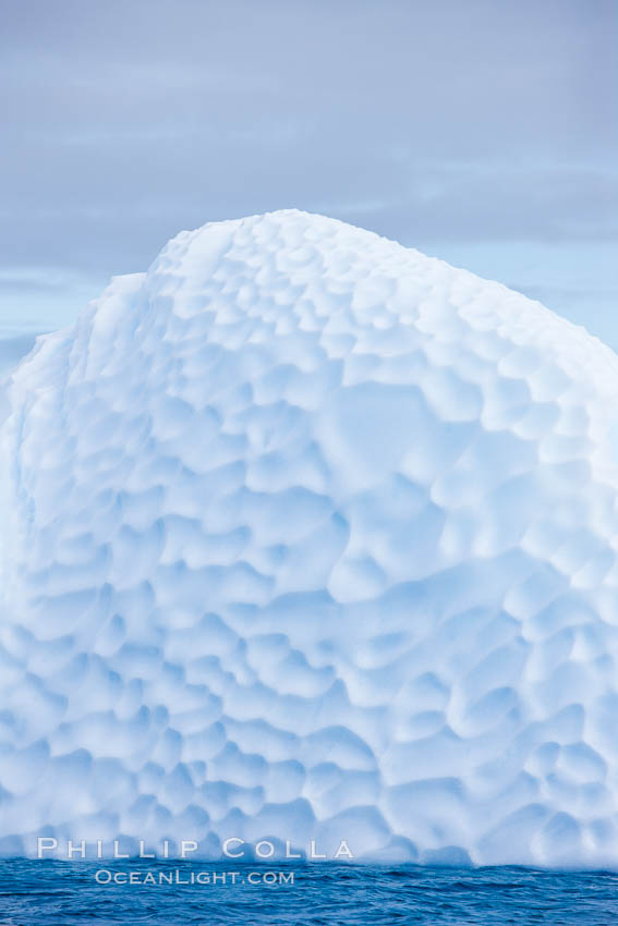 Iceberg with scalloped erosion.  The eroded indentations on this iceberg were melted when this portion of the iceberg was underwater.  As it melted, the iceberg grew topheavy, eventually flipping and exposing this interesting surface. Paulet Island, Antarctic Peninsula, Antarctica, natural history stock photograph, photo id 24898