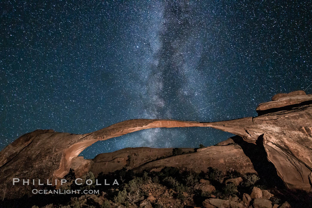 Landscape Arch and Milky Way galaxy. Stars rise over Landscape arch at night, filling the Utah sky, while the arch is gently lit by a hiker's light, Arches National Park