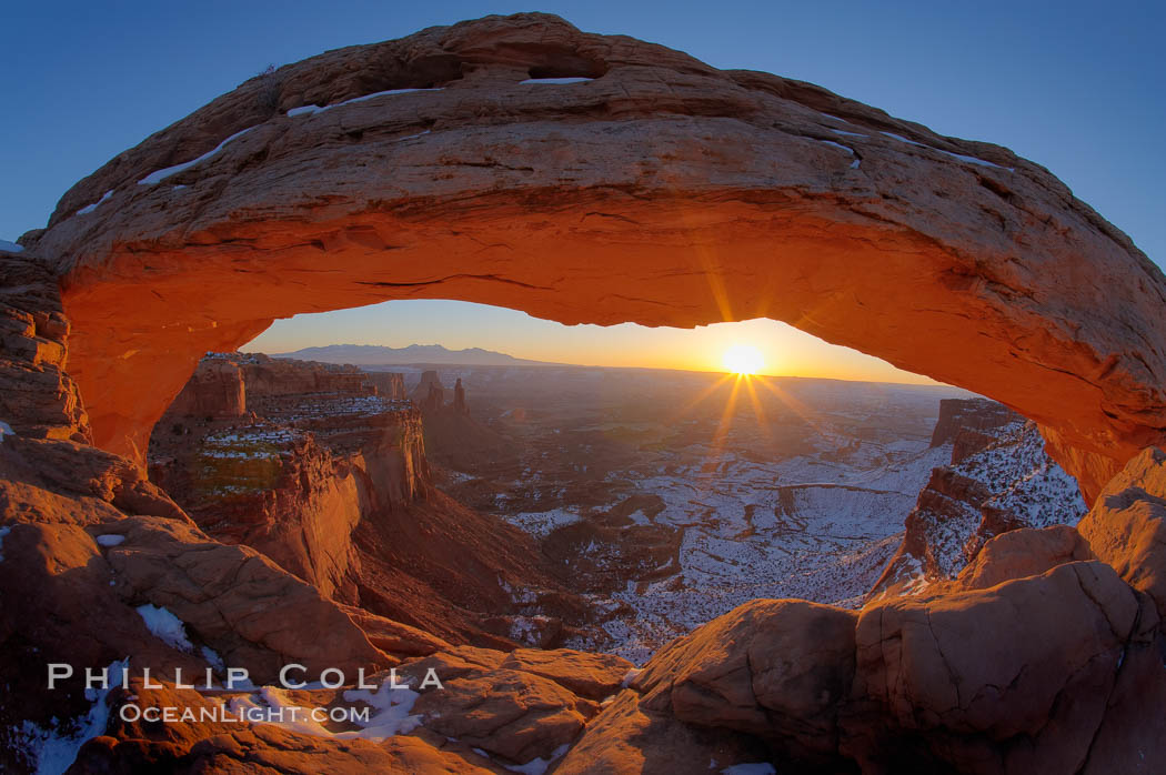 Mesa Arch spans 90 feet and stands at the edge of a mesa precipice thousands of feet above the Colorado River gorge. For a few moments at sunrise the underside of the arch glows dramatically red and orange, Island in the Sky, Canyonlands National Park, Utah