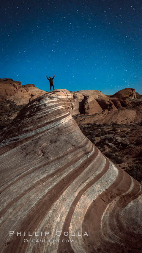 Exuberant hiker atop the Fire Wave, at night, stars and the evening sky. Valley of Fire State Park, Nevada, USA, natural history stock photograph, photo id 28450