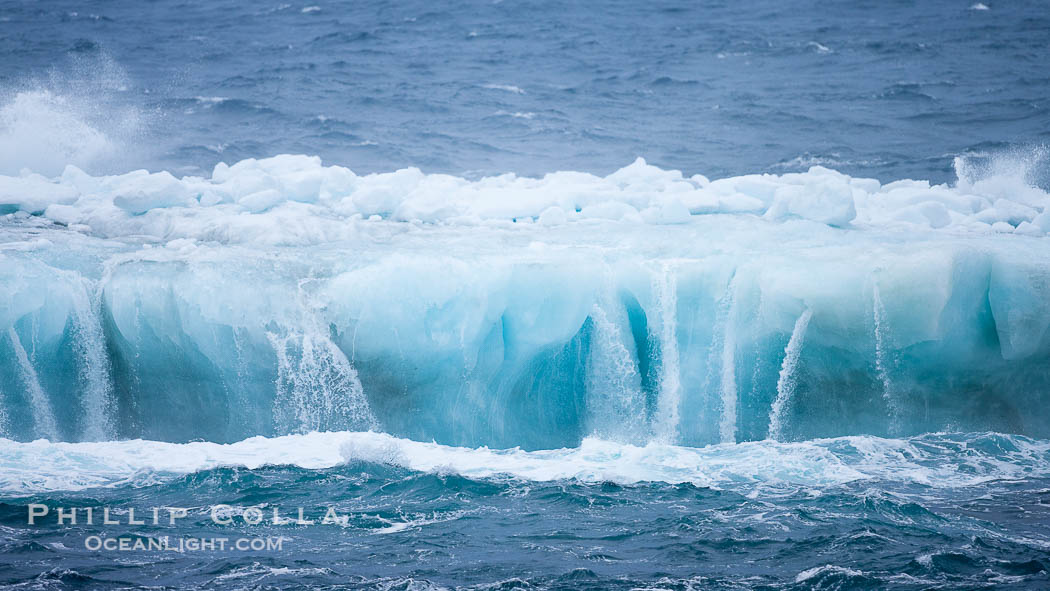 Ocean waves wash over a flat iceberg, carving gulleys into the sides of the iceberg., natural history stock photograph, photo id 24934