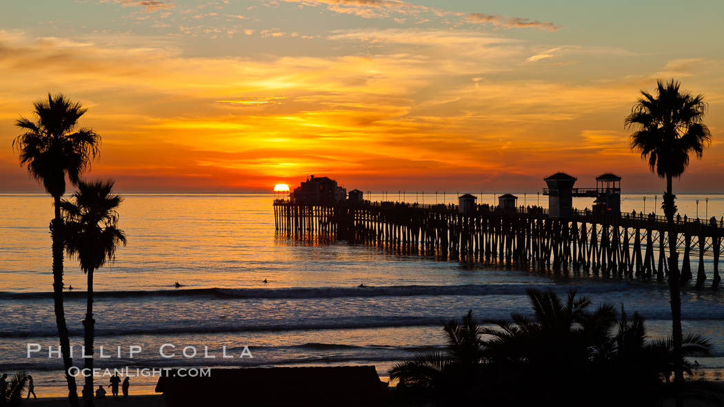 Oceanside Pier at sunset, clouds and palm trees with a brilliant sky at dusk