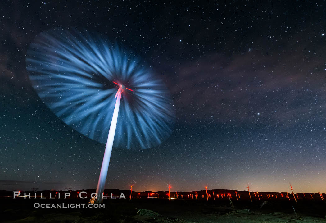 Stars rise above the Ocotillo Wind Turbine power generation facility, with a flashlight illuminating the turning turbine blades