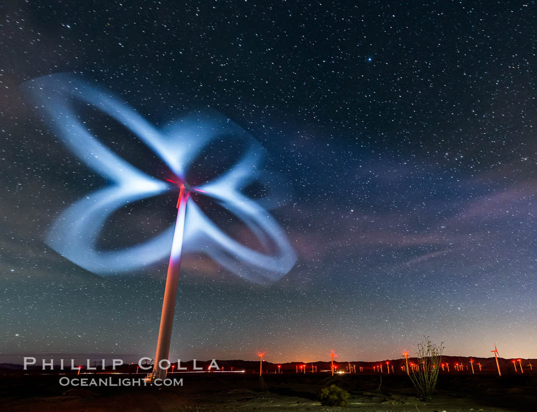 Stars rise above the Ocotillo Wind Turbine power generation facility, with a flashlight illuminating the turning turbine blades