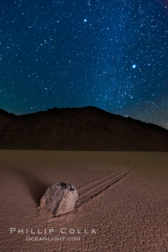 Racetrack sailing stone and Milky Way, at night. A sliding rock of the Racetrack Playa. The sliding rocks, or sailing stones, move across the mud flats of the Racetrack Playa, leaving trails behind in the mud. The explanation for their movement is not known with certainty, but many believe wind pushes the rocks over wet and perhaps icy mud in winter. Death Valley National Park, California, USA, natural history stock photograph, photo id 27641