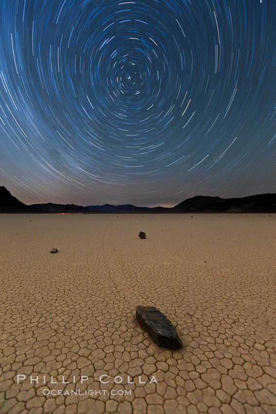 Racetrack sailing stone and star trails.  A sliding rock of the Racetrack Playa. The sliding rocks, or sailing stones, move across the mud flats of the Racetrack Playa, leaving trails behind in the mud. The explanation for their movement is not known with certainty, but many believe wind pushes the rocks over wet and perhaps icy mud in winter. Death Valley National Park, California, USA, natural history stock photograph, photo id 27668