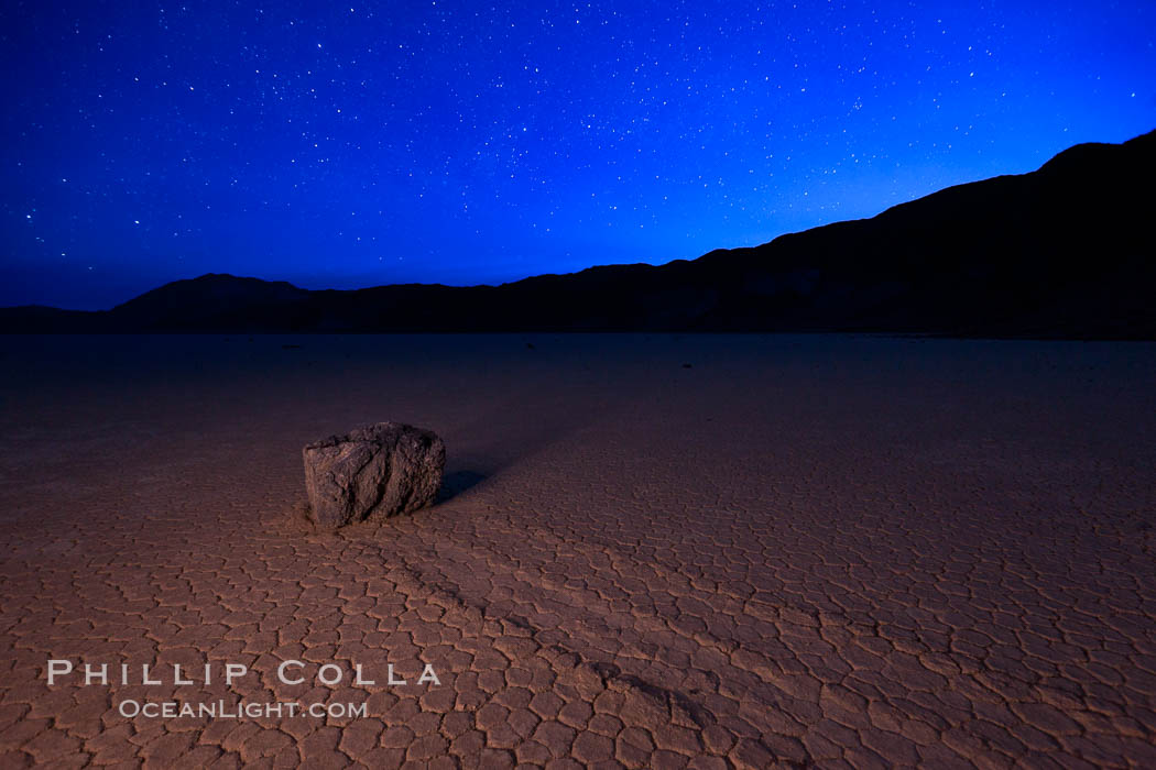 Racetrack sailing stone and stars at night. A sliding rock of the Racetrack Playa. The sliding rocks, or sailing stones, move across the mud flats of the Racetrack Playa, leaving trails behind in the mud. The explanation for their movement is not known with certainty, but many believe wind pushes the rocks over wet and perhaps icy mud in winter. Death Valley National Park, California, USA, natural history stock photograph, photo id 27637
