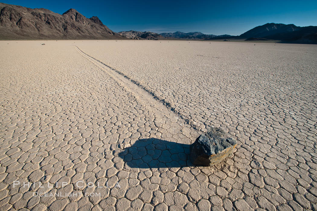 Sailing stone on the Death Valley Racetrack playa.  The sliding rocks, or sailing stones, move across the mud flats of the Racetrack Playa, leaving trails behind in the mud.  The explanation for their movement is not known with certainty, but many believe wind pushes the rocks over wet and perhaps icy mud in winter. Death Valley National Park, California, USA, natural history stock photograph, photo id 25321