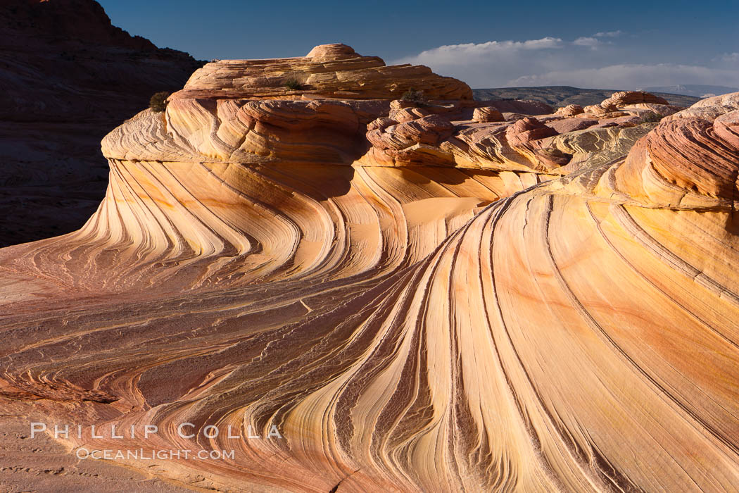 The Second Wave at sunset. The Second Wave, a curiously-shaped sandstone swirl, takes on rich warm tones and dramatic shadowed textures at sunset. Set in the North Coyote Buttes of Arizona and Utah, the Second Wave is characterized by striations revealing layers of sedimentary deposits, a visible historical record depicting eons of submarine geology, Paria Canyon-Vermilion Cliffs Wilderness