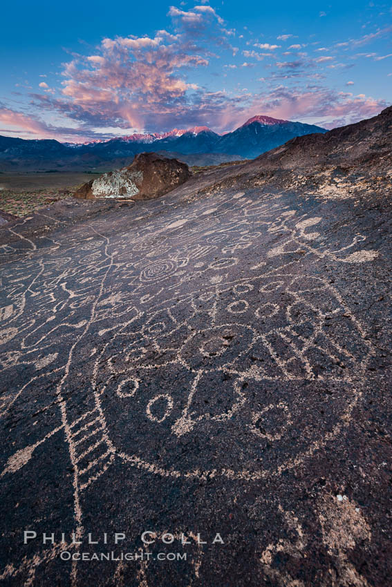 Sky Rock petroglyphs near Bishop, California, sunrise light just touching clouds and the Sierra Nevada. Hidden atop an enormous boulder in the Volcanic Tablelands lies Sky Rock, a set of petroglyphs that face the sky. These superb examples of native American petroglyph artwork are thought to be Paiute in origin, but little is known about them