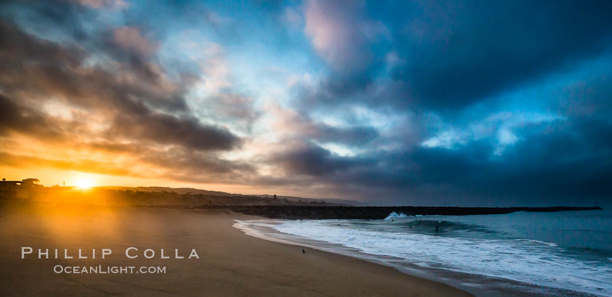 Sunrise at the Wedge. The Wedge, a notorious and famous shorebreak at the end of the Newport Peninsula, is seen here under a huge dawning sky and sporting a small but fun swell, Newport Beach, California