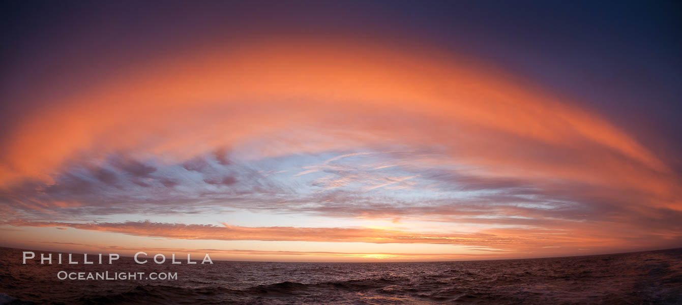 Sunset clouds create a colorful arch, spanning the heavens from horizon to horizon, over the open sea between the Falkland Islands and South Georgia Island