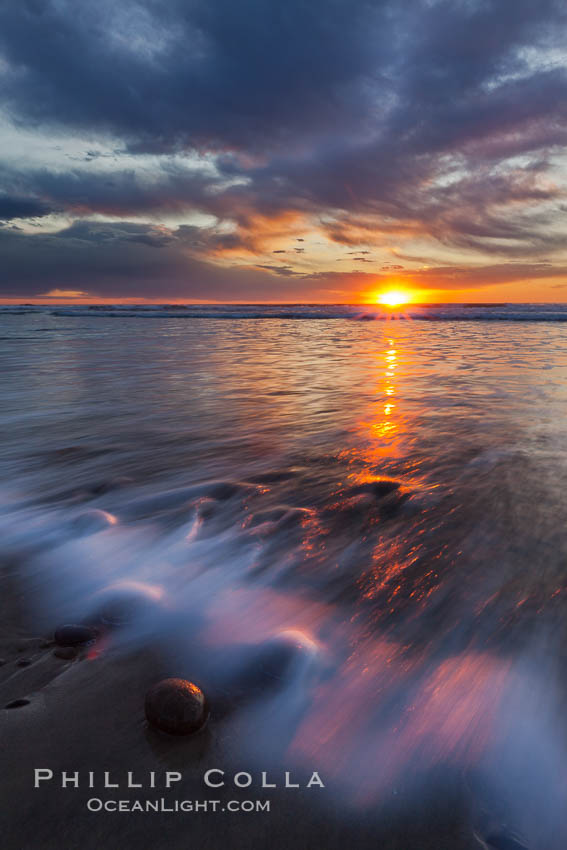 Surf and sky at sunset, waves crash upon the sand at dusk, Carlsbad, California