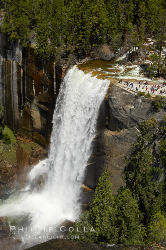 Vernal Falls at peak flow in late spring. Hikers are seen at the precipice to Vernal Falls, having hiked up the Mist Trail to get there, Yosemite National Park, California