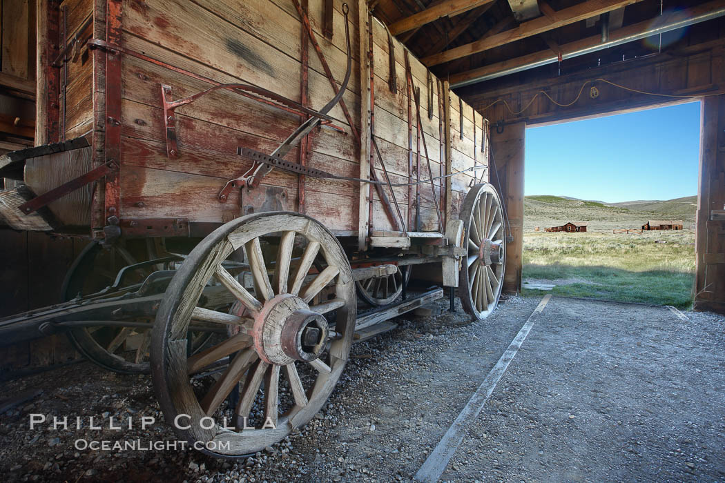 Wagon and interior of County Barn, Brown House and Moyle House in distance, Bodie State Historical Park, California