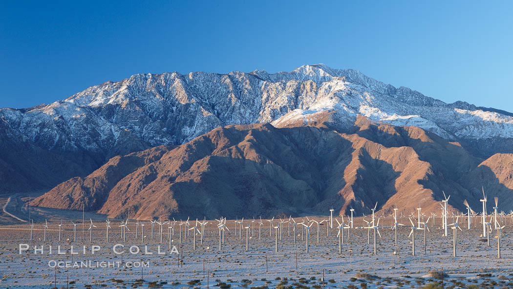 Wind turbines, rise above the flat floor of the San Gorgonio Pass near Palm Springs, with snow covered Mount San Jacinto in the background, provide electricity to Palm Springs and the Coachella Valley. California, USA, natural history stock photograph, photo id 22210