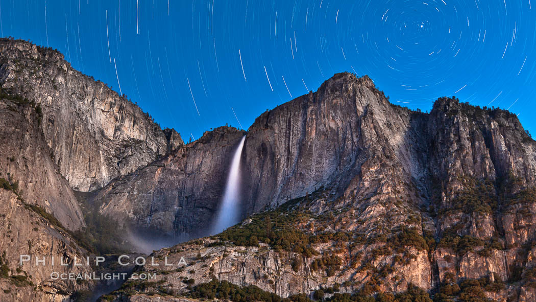 Yosemite Falls and star trails, night sky time exposure of Yosemite Falls waterfall in full spring flow, with star trails arcing through the night sky, Yosemite National Park, California